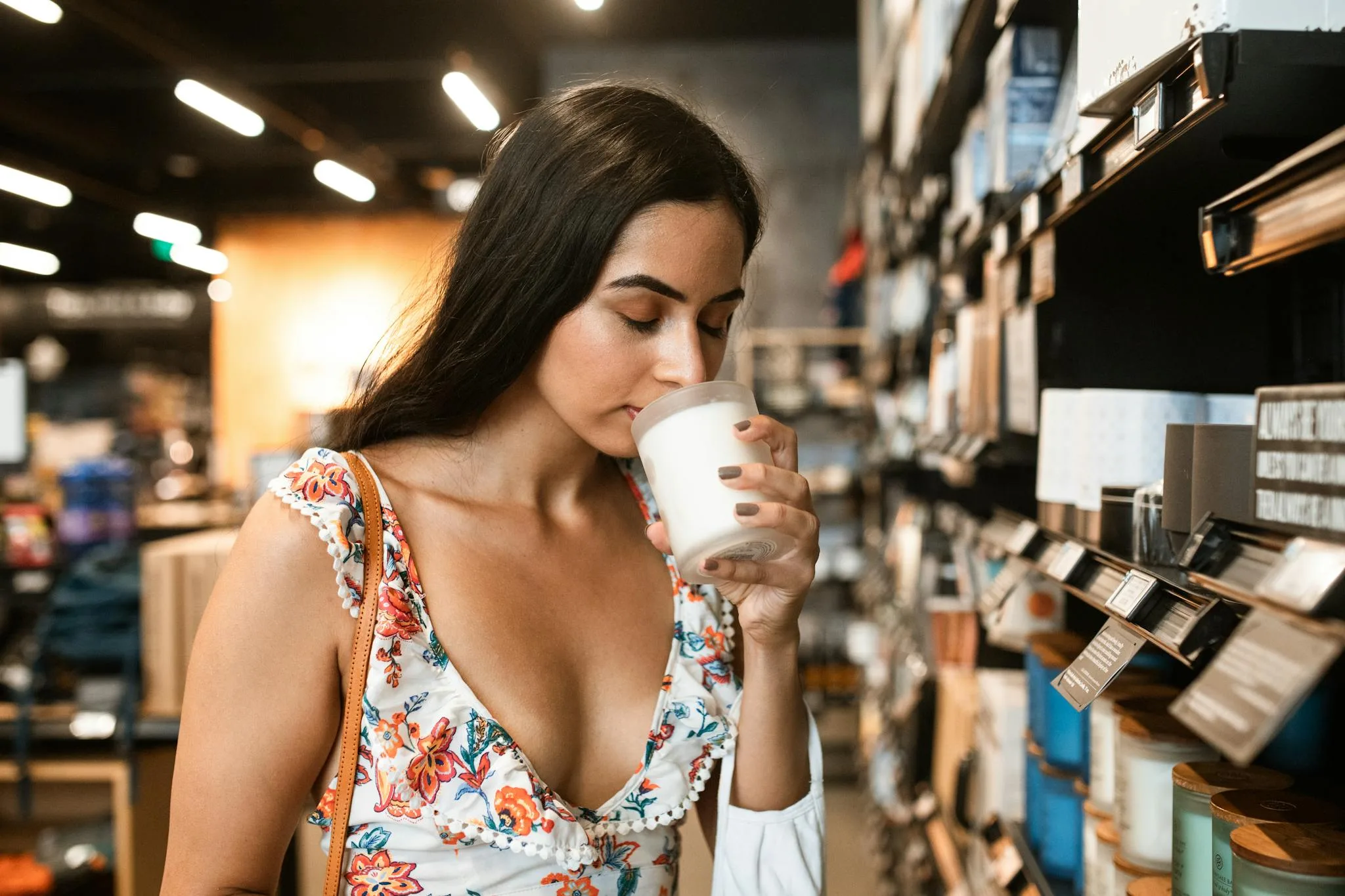 Woman in Floral Dress Smelling Candle with Closed Eyes